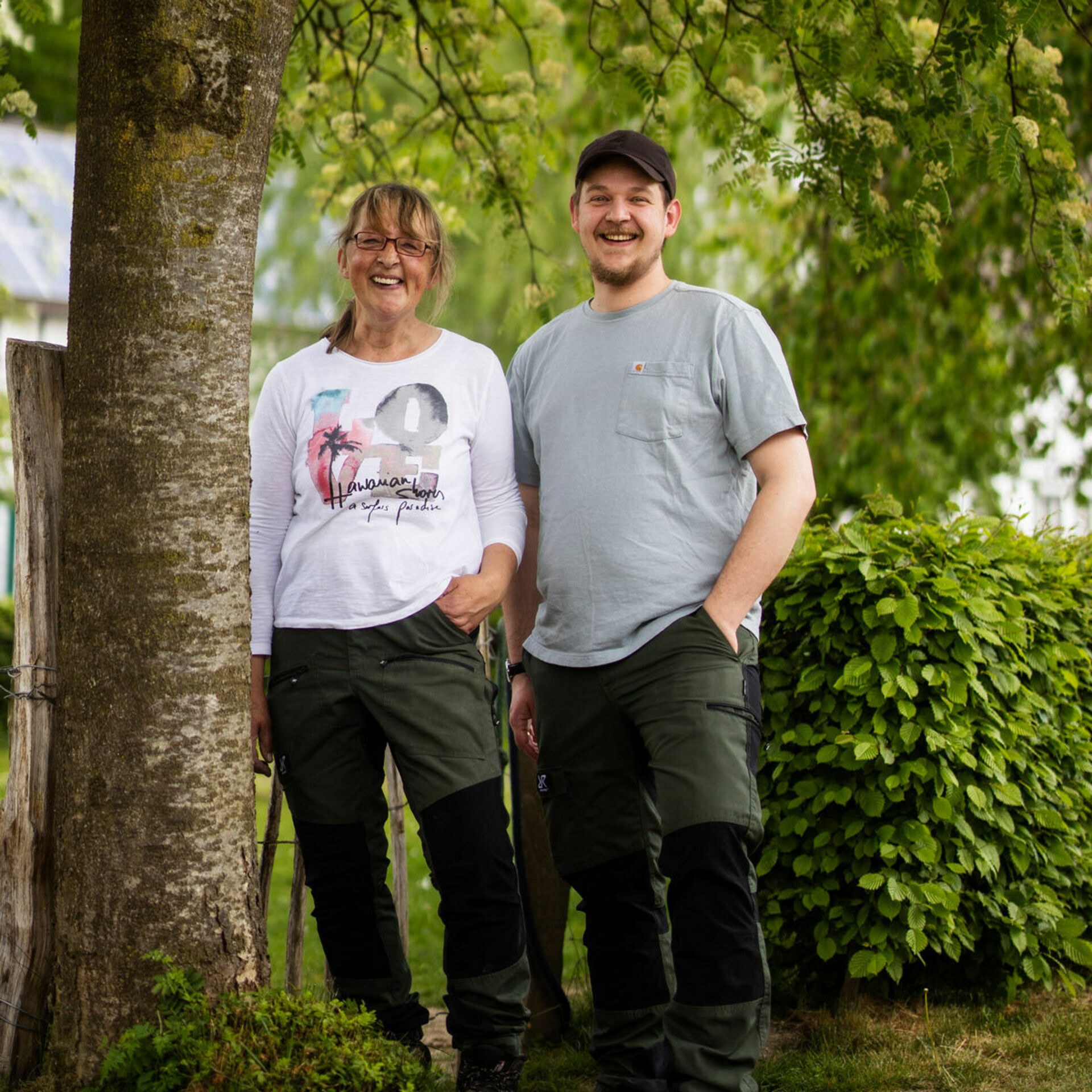 Gastgeberfamilie Arm in Arm vor Baum 